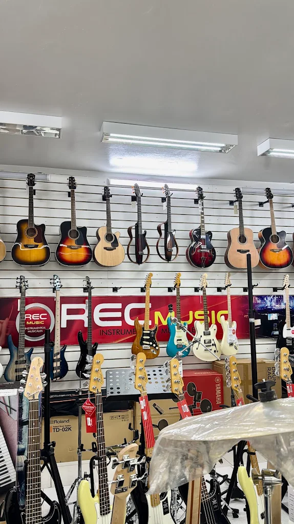 Showroom REC Music com guitarras, baixos e equipamentos no palco da loja